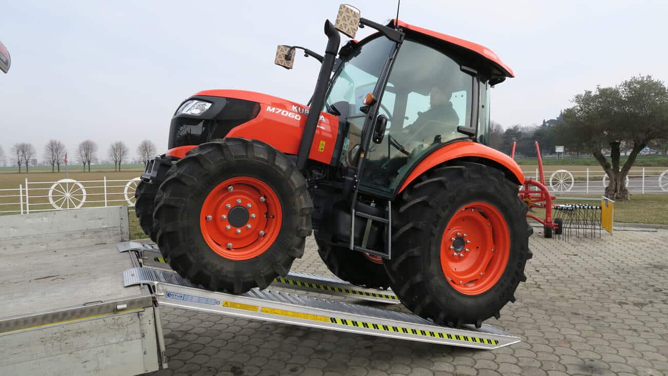 Trattore rosso su rampe di carico che sale sul camion