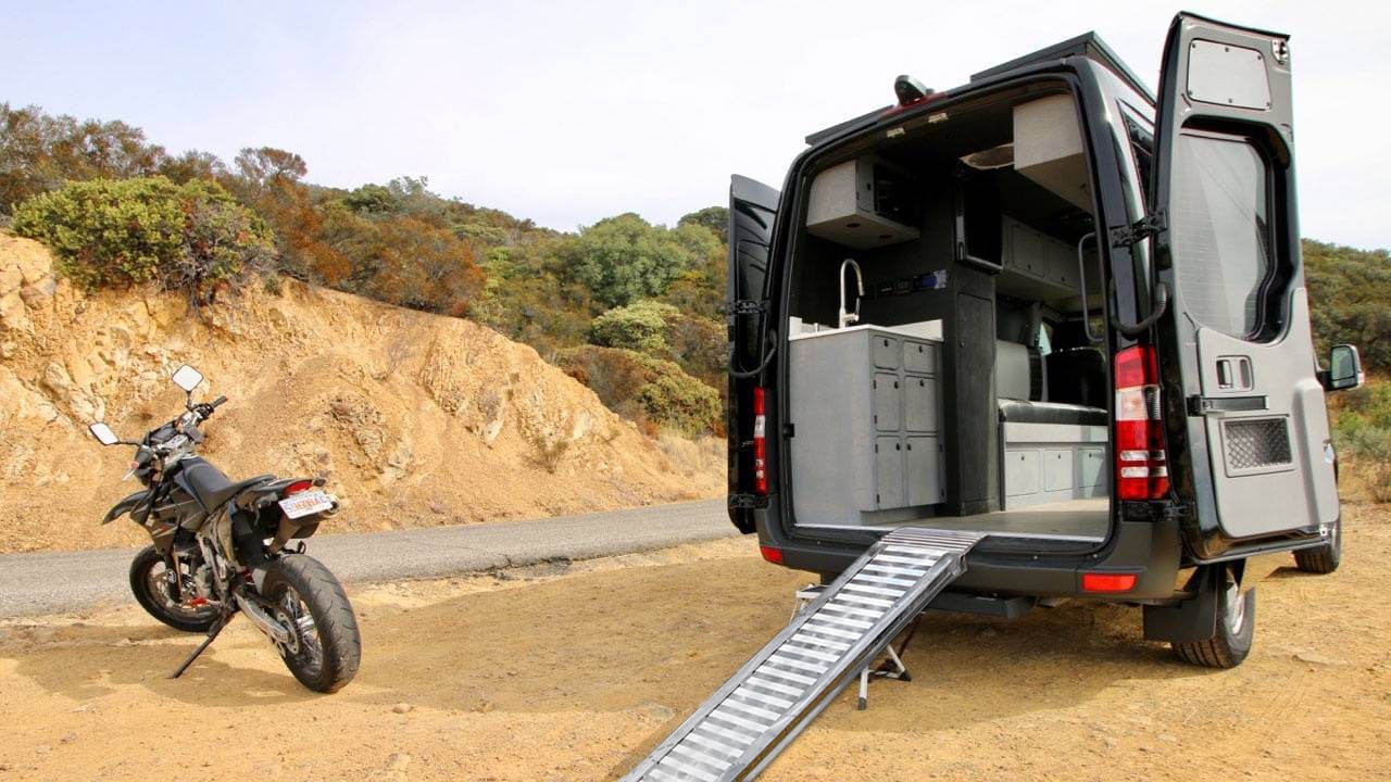 van con appoggiata una rampa di alluminio leggera per il cario della moto parcheggiata alla sinistra